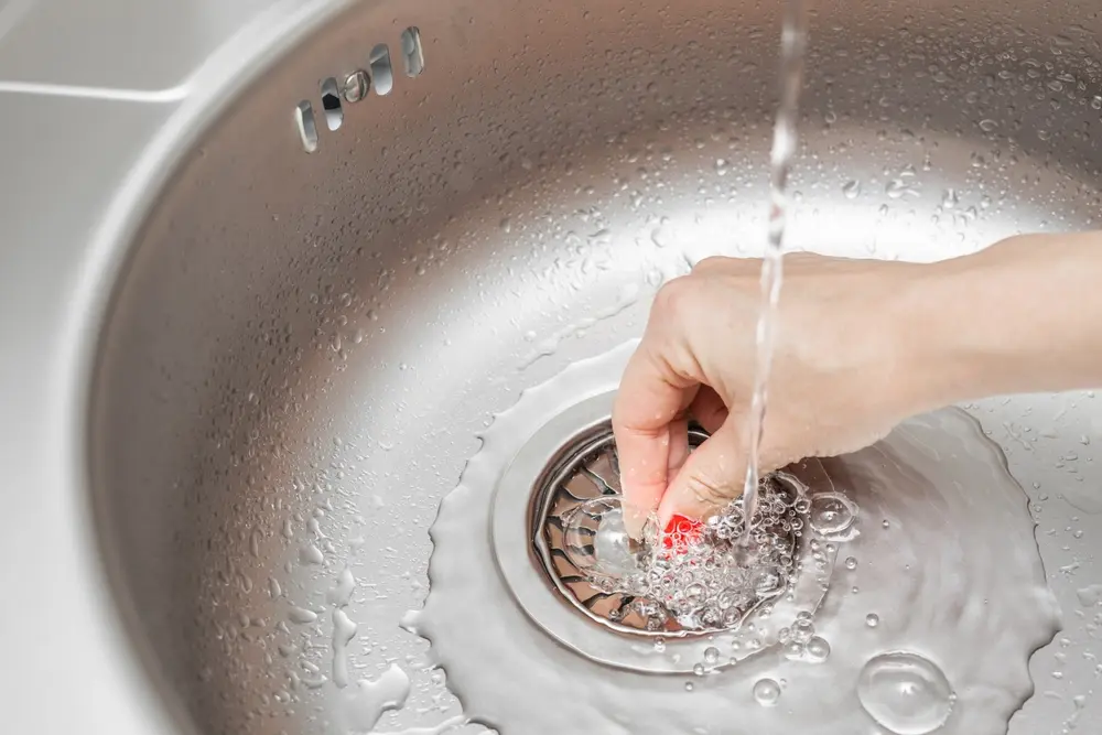 woman's hand with sink plug. why is my sink gurgling