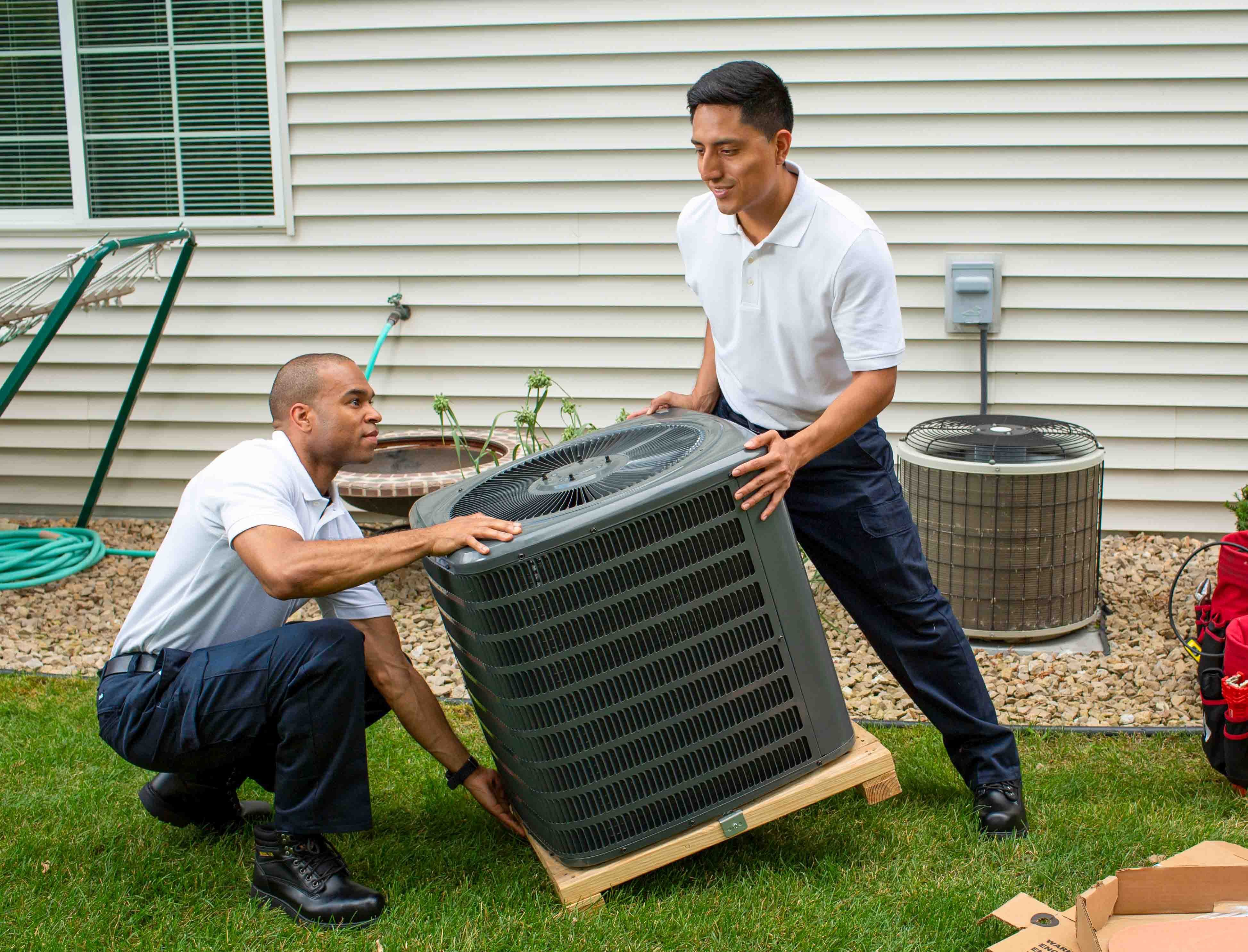 Two men moving an AC