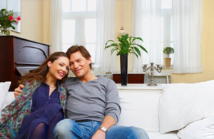 a smiling young couple on their living room couch