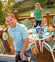 A father grilling food for his wife and children on the porch