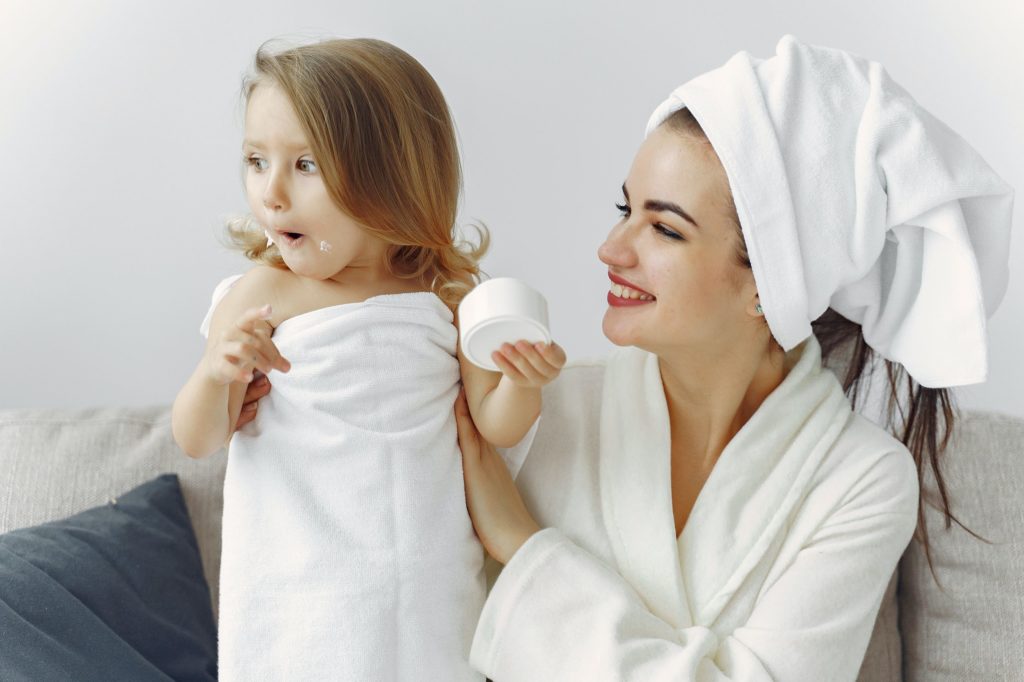 Smiling mother and daughter in bath towel and robe after hot water heater repair