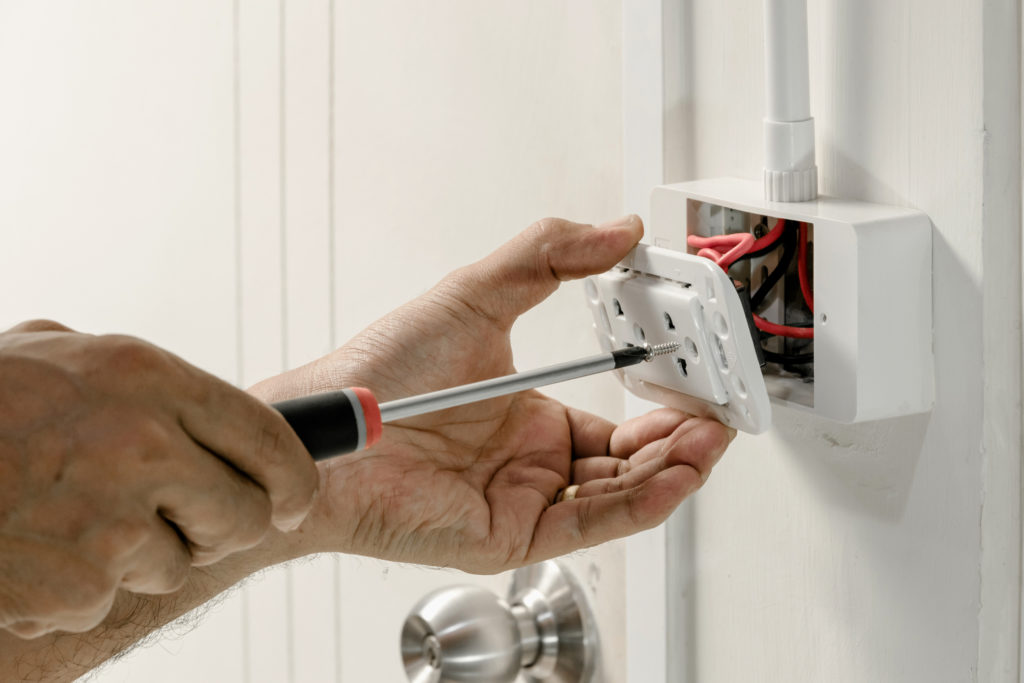 Closeup of hands screwing in an outlet